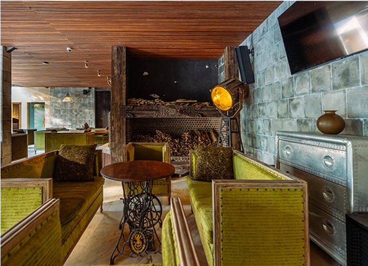 Lounge with timber ceilings, green sofas and a wood stove.